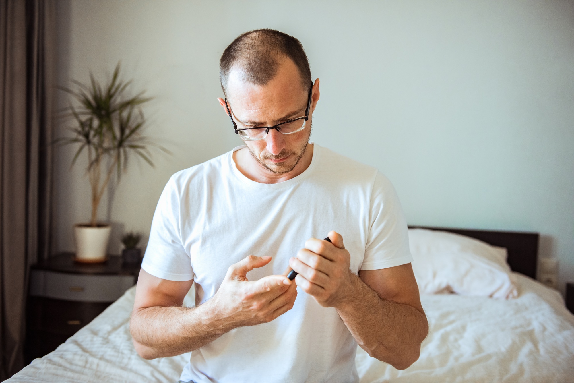 Diabetic man taking blood sample with lancet pen at home. Conceptual close up for diabetes, glycemia