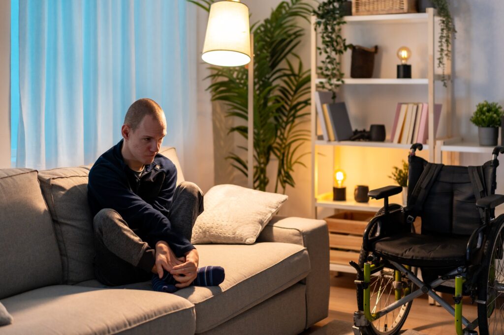Disabled man sitting on sofa with sad expression