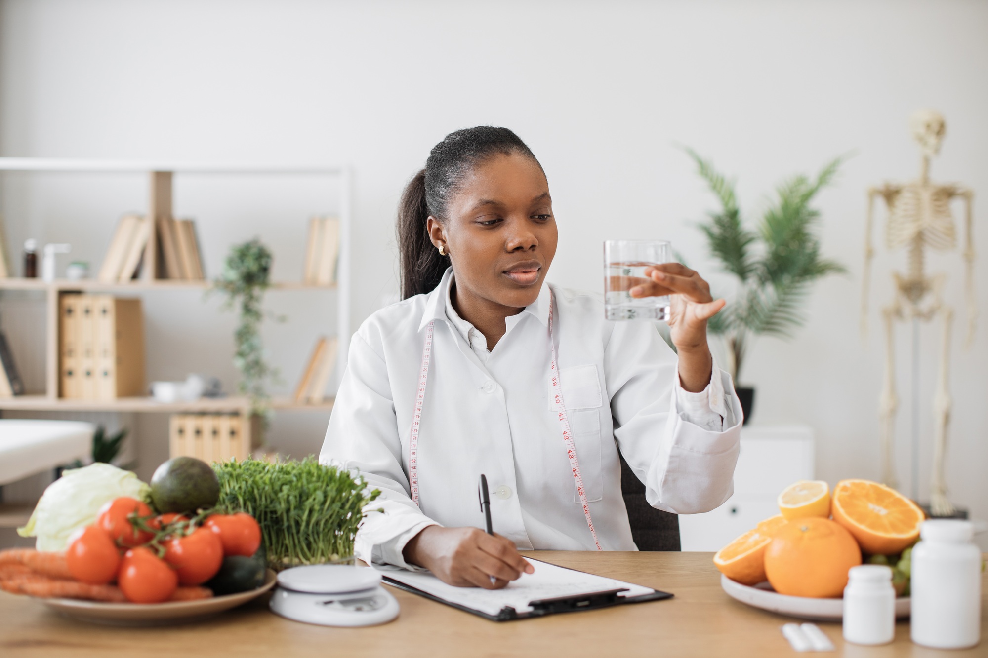 Nutrition specialist checking fluid in glass at workplace