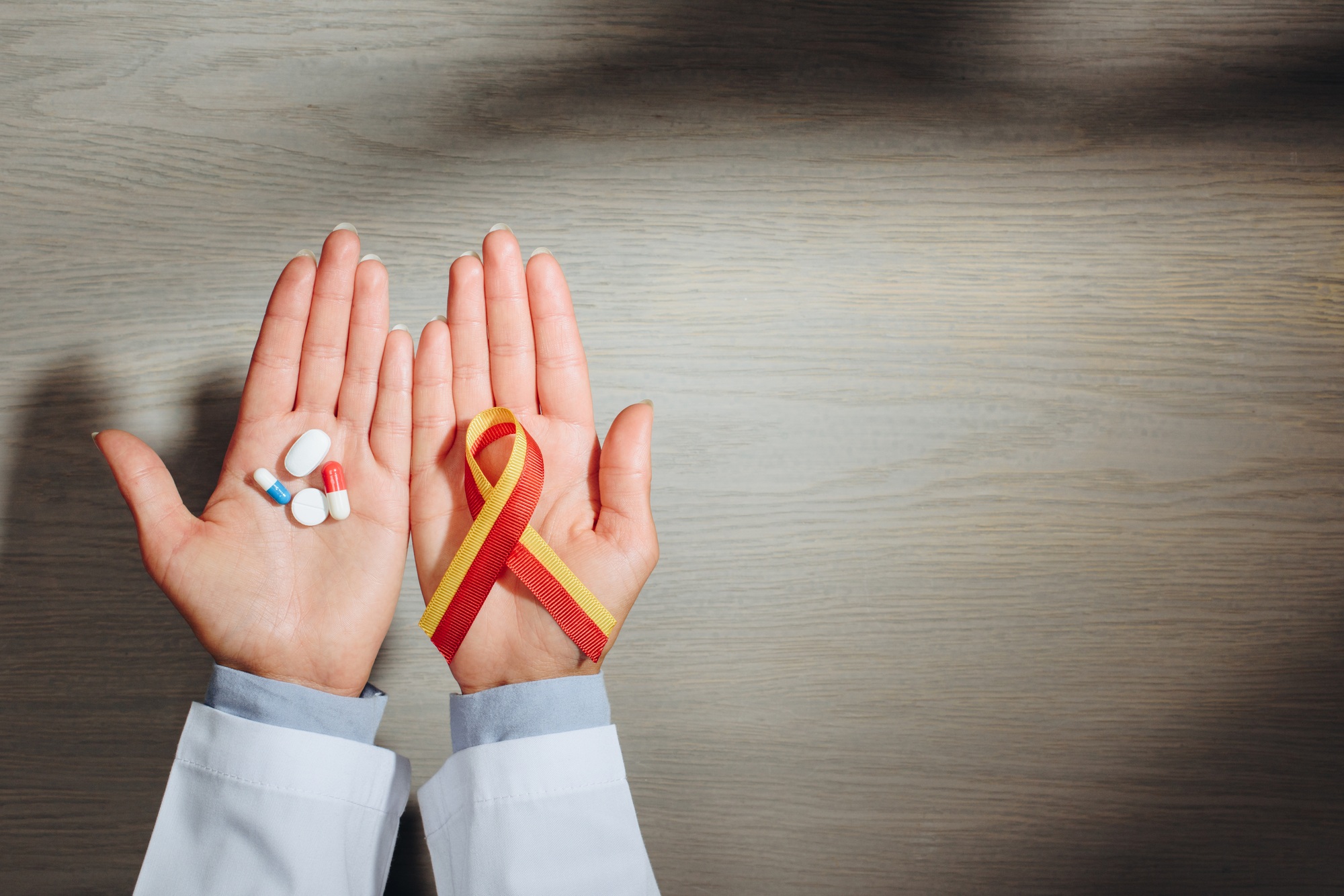 partial view of female doctor holding ribbon and pills, world hepatitis day concept