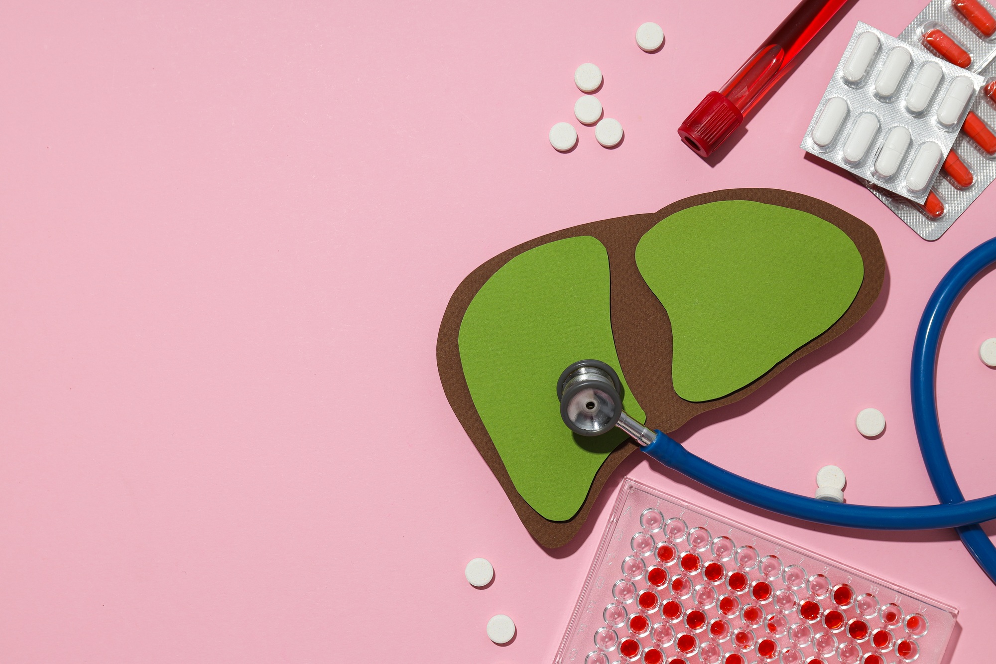 Pills, stethoscope and paper mockup of liver on pink background, space for text