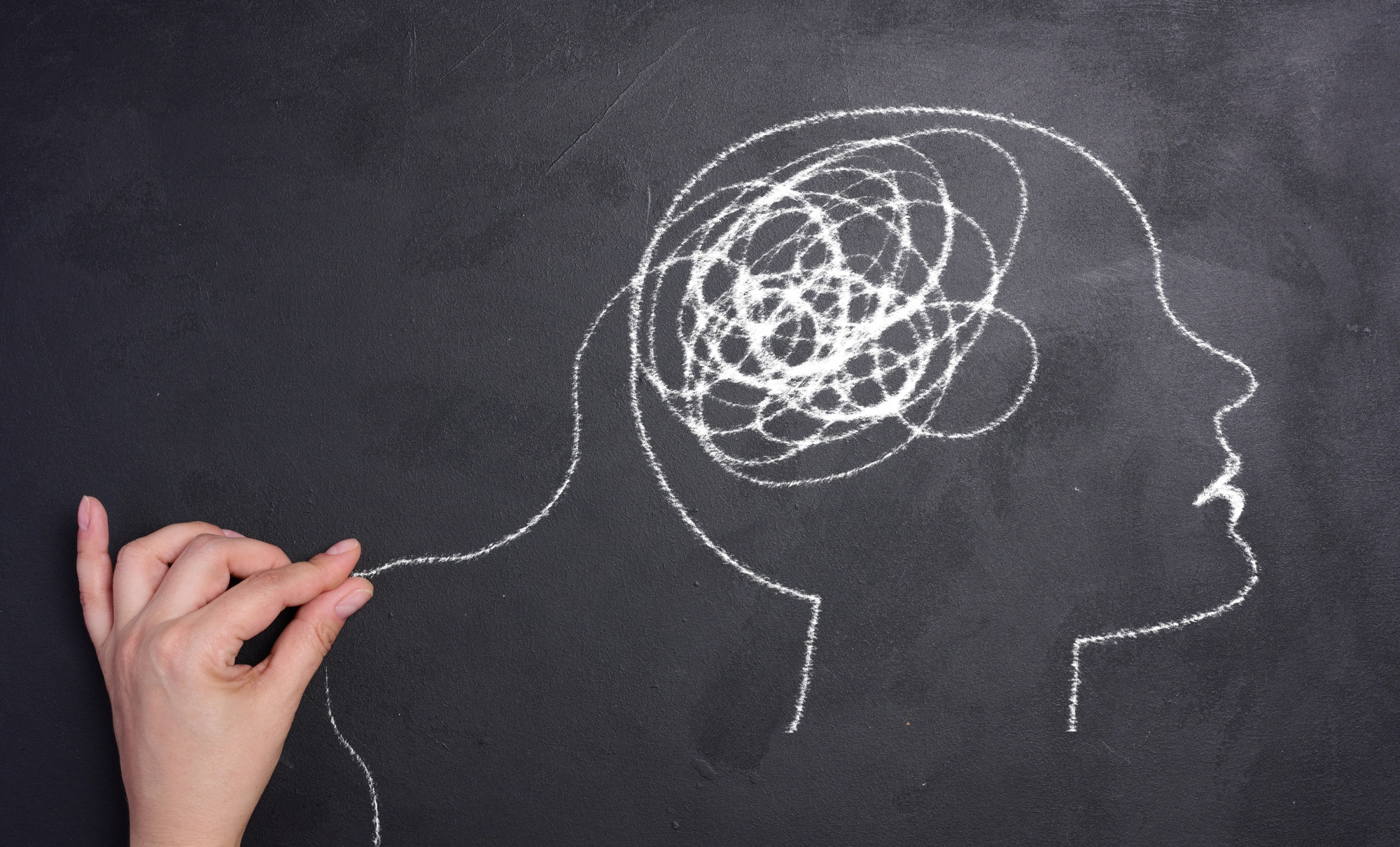 Profile of a human head with a tangled spiral in the brain area. The head is drawn in white chalk.