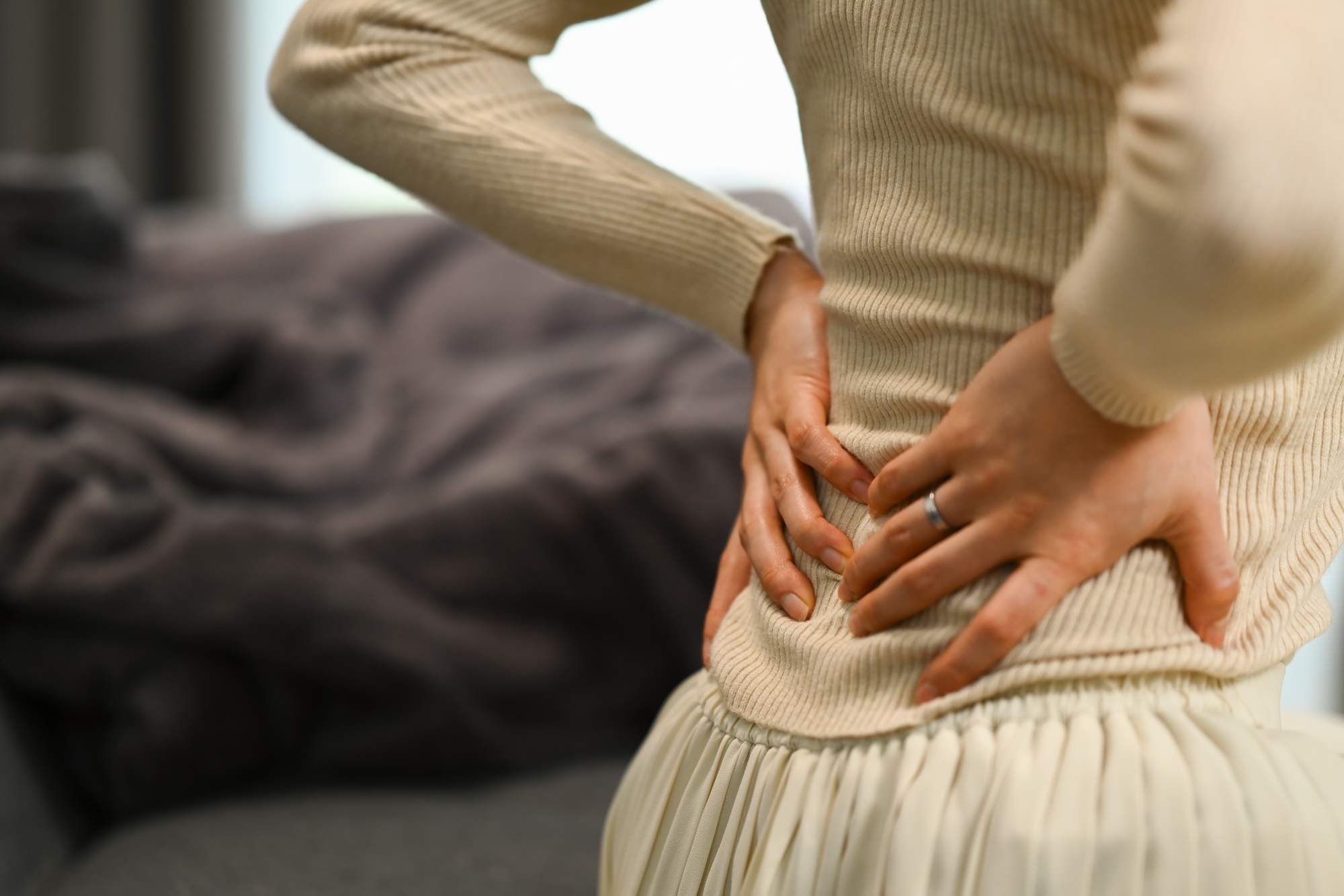 Unrecognizable woman suffering from lower lumbar backache, kidney disease.