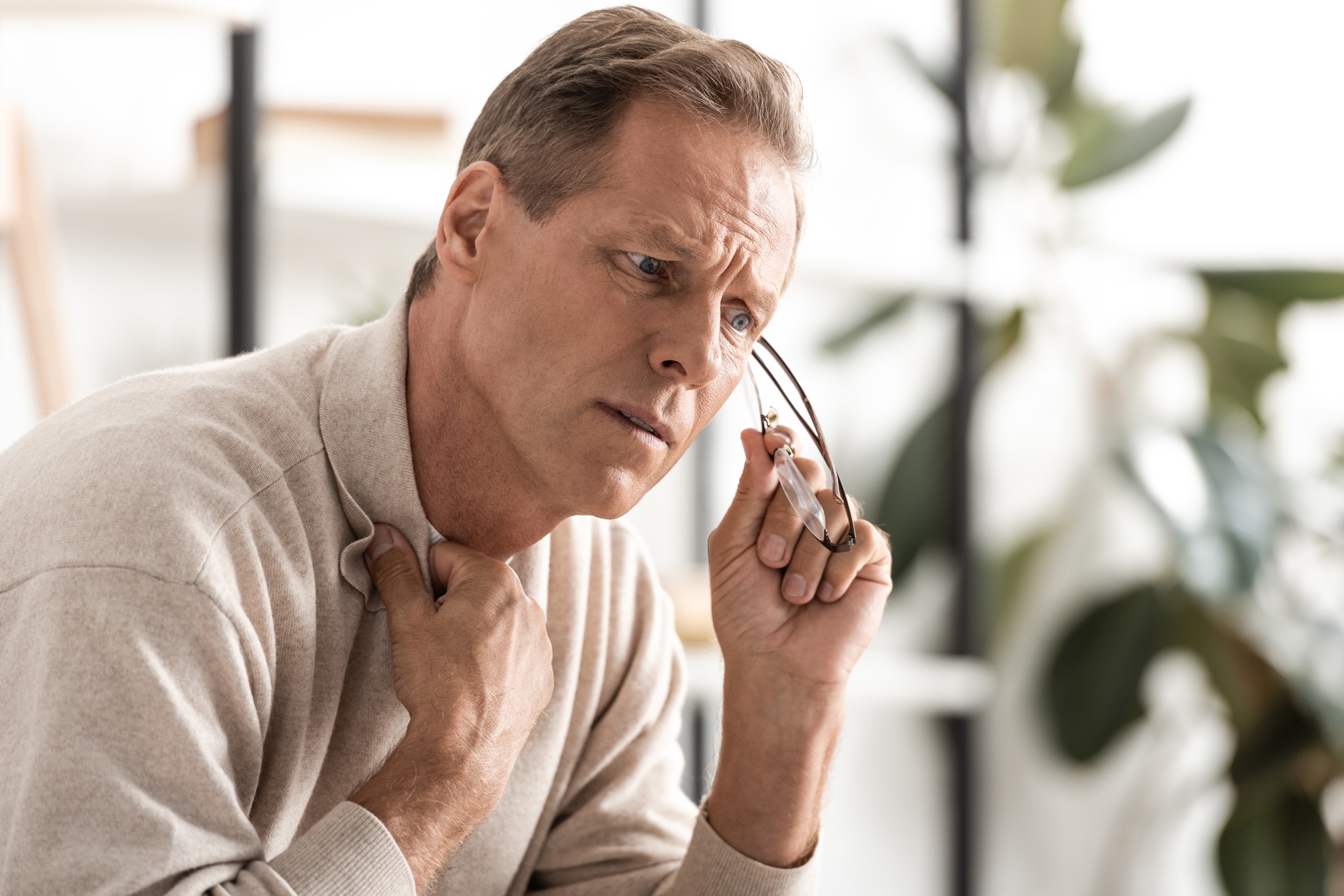 upset senior man with alzheimer disease holding glasses