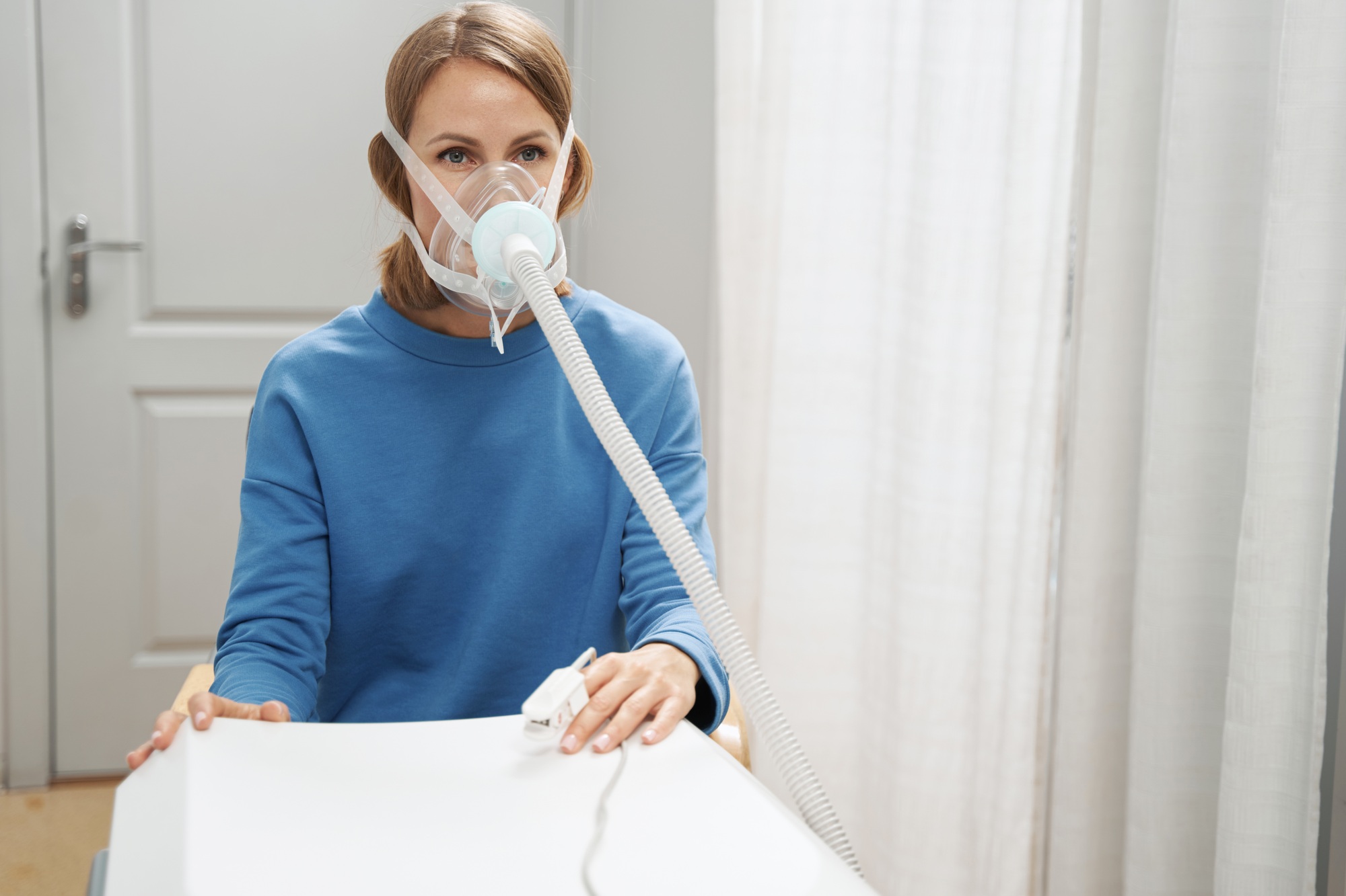 Woman using breathing therapy medical device in clinic