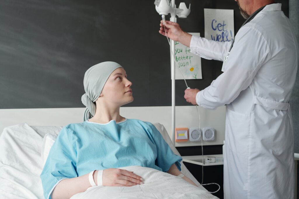 Young female patient with cancer looking at oncologist preparing dropper